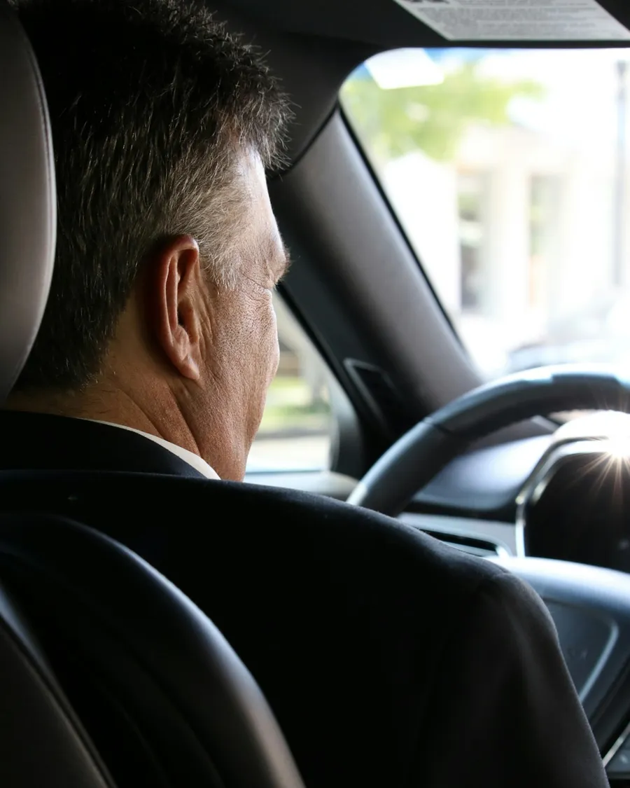 Chauffeur de taxi en costume au volant de sa berline
