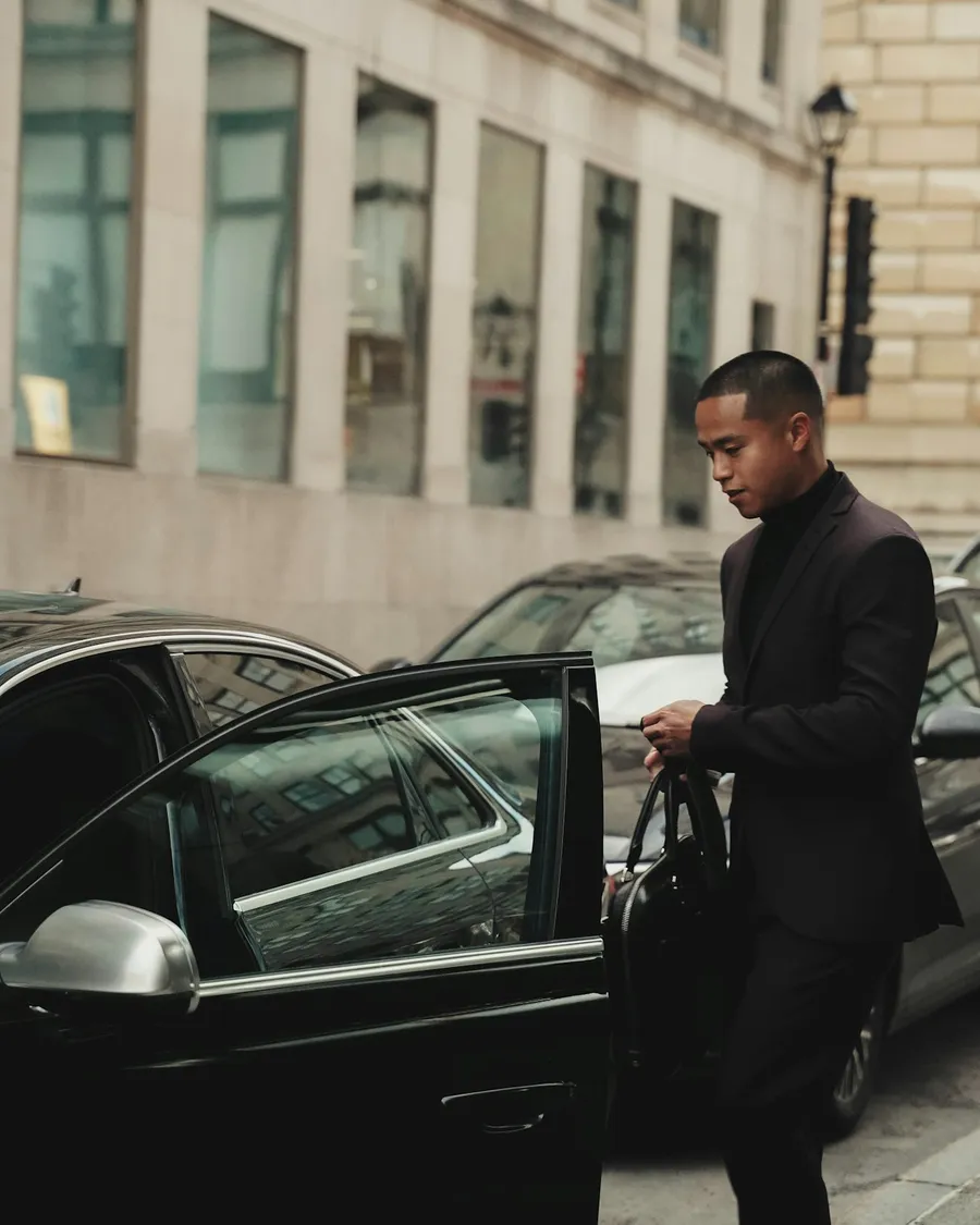Chauffeur ouvrant la portière arrière d'une berline pour son passager